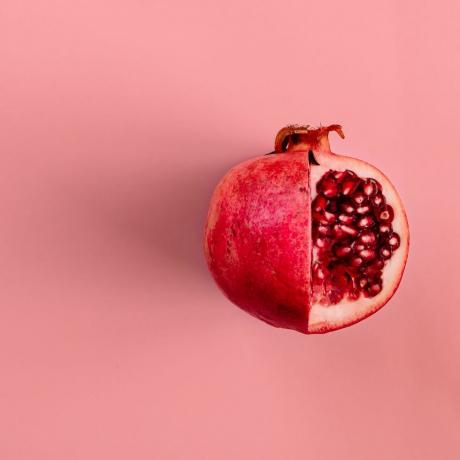 червен плод от нар на пастелно розов фон